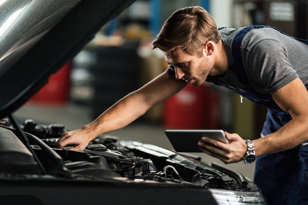 Prüfer untersucht den Motorraum eines Fahrzeugs